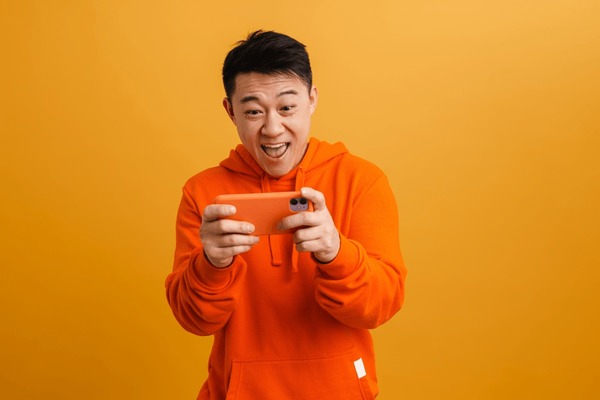 Asian Man Is Playing Mobile Game Seriously. Stock Photo, Picture