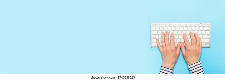 Female hands on a keyboard on a blue background. Concept of office work, freelance, online. Banner. Flat lay, top view Foto Stok