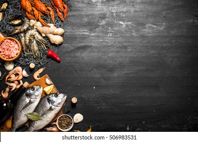 Стоковая фотография: Fresh seafood. Two fresh fish with a bottle of wine. On a black chalkboard.