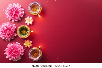 Стоковая фотография: Happy Diwali - Clay Diya lamps lit during Diwali, Hindu festival of lights celebration. Colorful traditional oil lamp diya on red background