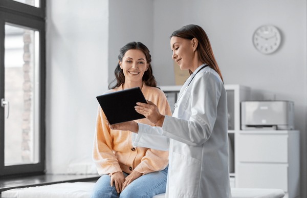 Medizin, Gesundheitswesen und Menschen Konzept - weibliche Ärztin mit Tablet-PC-Computer, die mit einer lächelnden Patientin im Krankenhaus spricht – Stockfoto