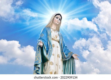 Estatua de Nuestra Señora de la Virgen de la gracia María con el cielo azul brillante y hermosas nubes con fondo de color abstracto y papel tapiz en Tailandia. Foto de stock