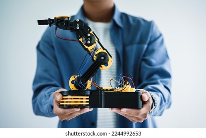 teenager students doing robot arm homework project in house disassemble the circuit and coding. technology of robotics programing and STEM education concept. Stock Photo