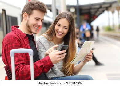 Tourists travelers consulting gps and guide from a smart phone in a train station Stock-foto