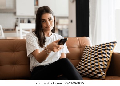 Young woman sitting on couch at home watching tv Stock Photo