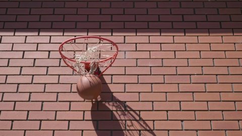 Front shot of basketball going swish into net on red brick wall background to score goal. Stock Video