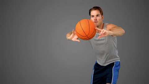 Basketball player passing the ball in slow motion on grey background Video stock